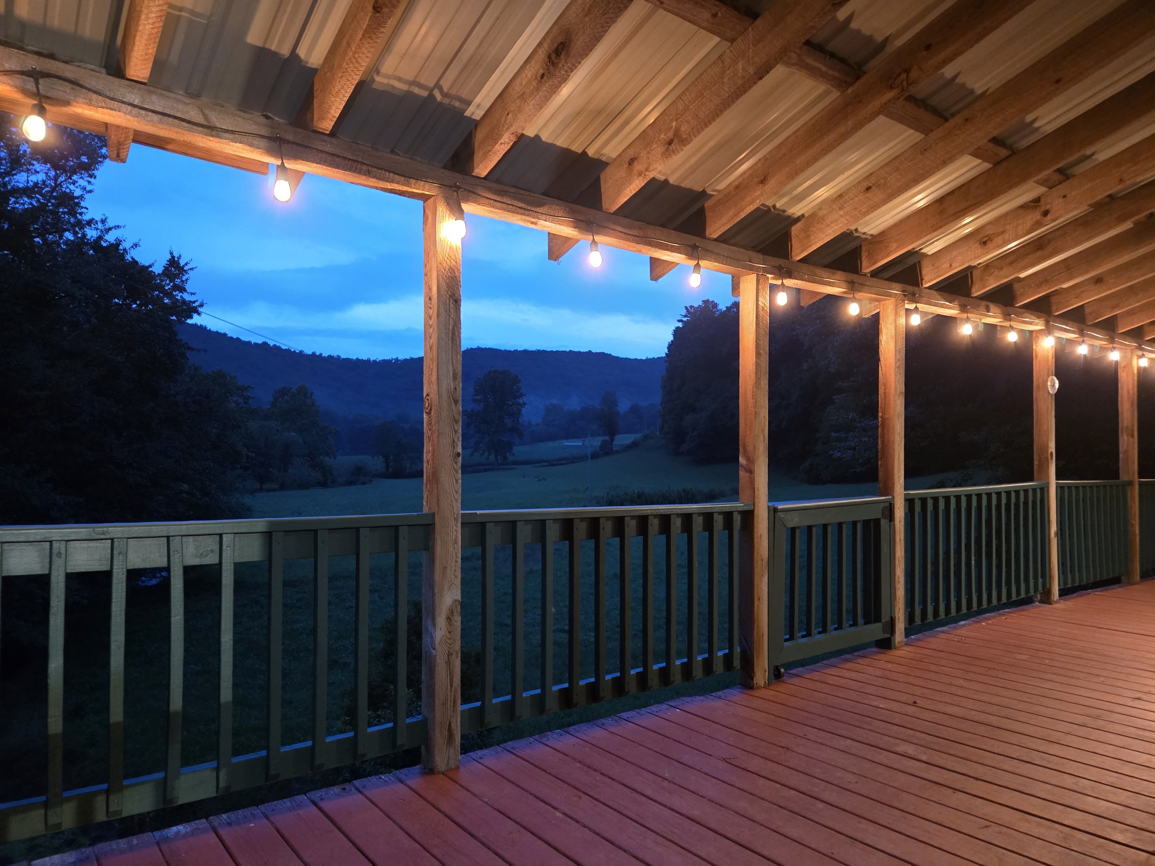 Headwaters porch at dusk with string lights glowing and mountain valley in the background